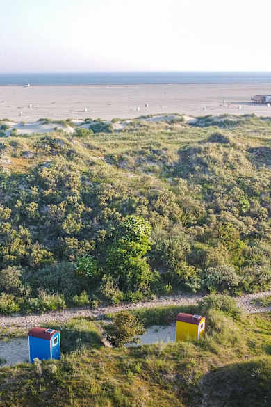 Blick auf einen Strand mit kleinen bunten Häuschen in den Dünen